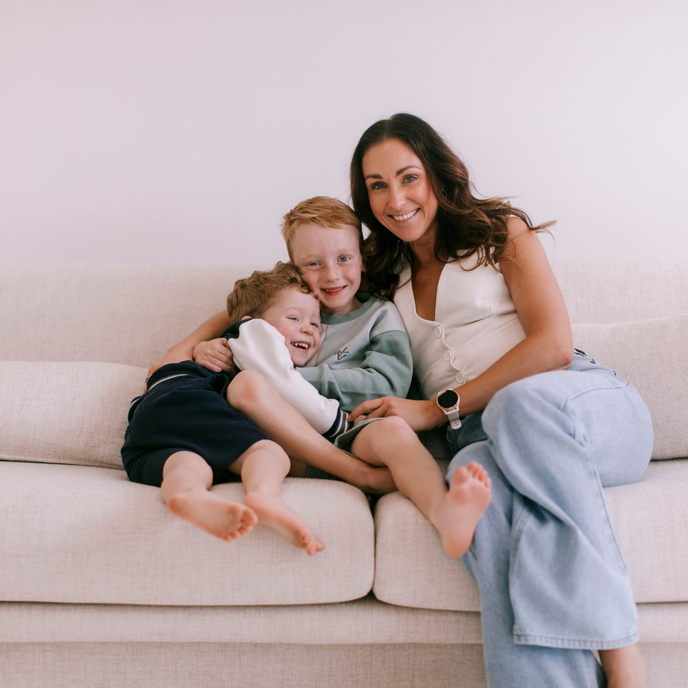 Women cuddling kids on couch